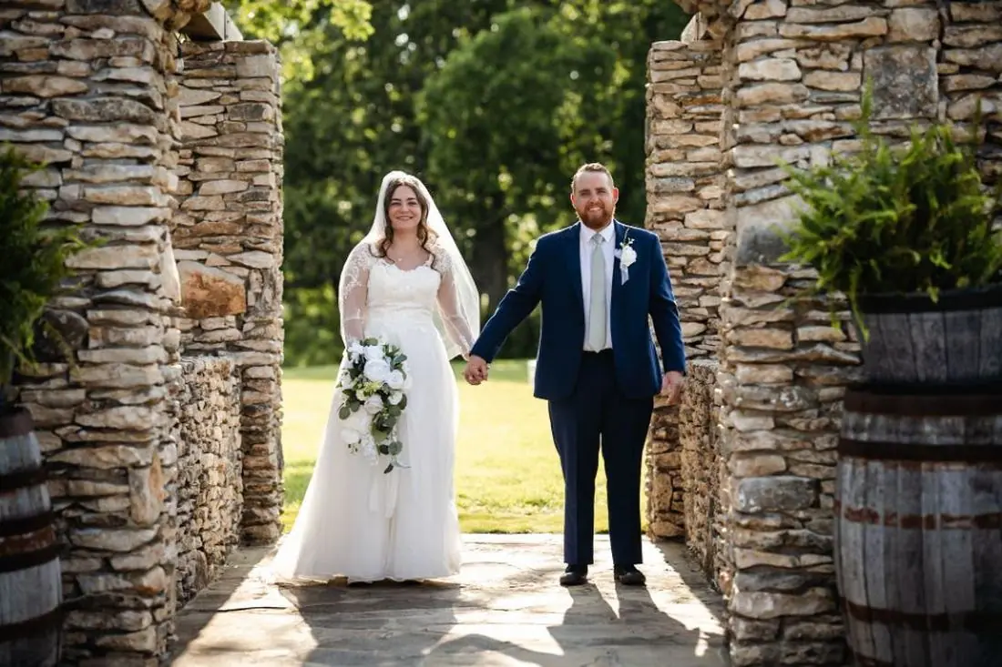 Bride and groom holding hands stone archway outdoor Oklahoma wedding photography