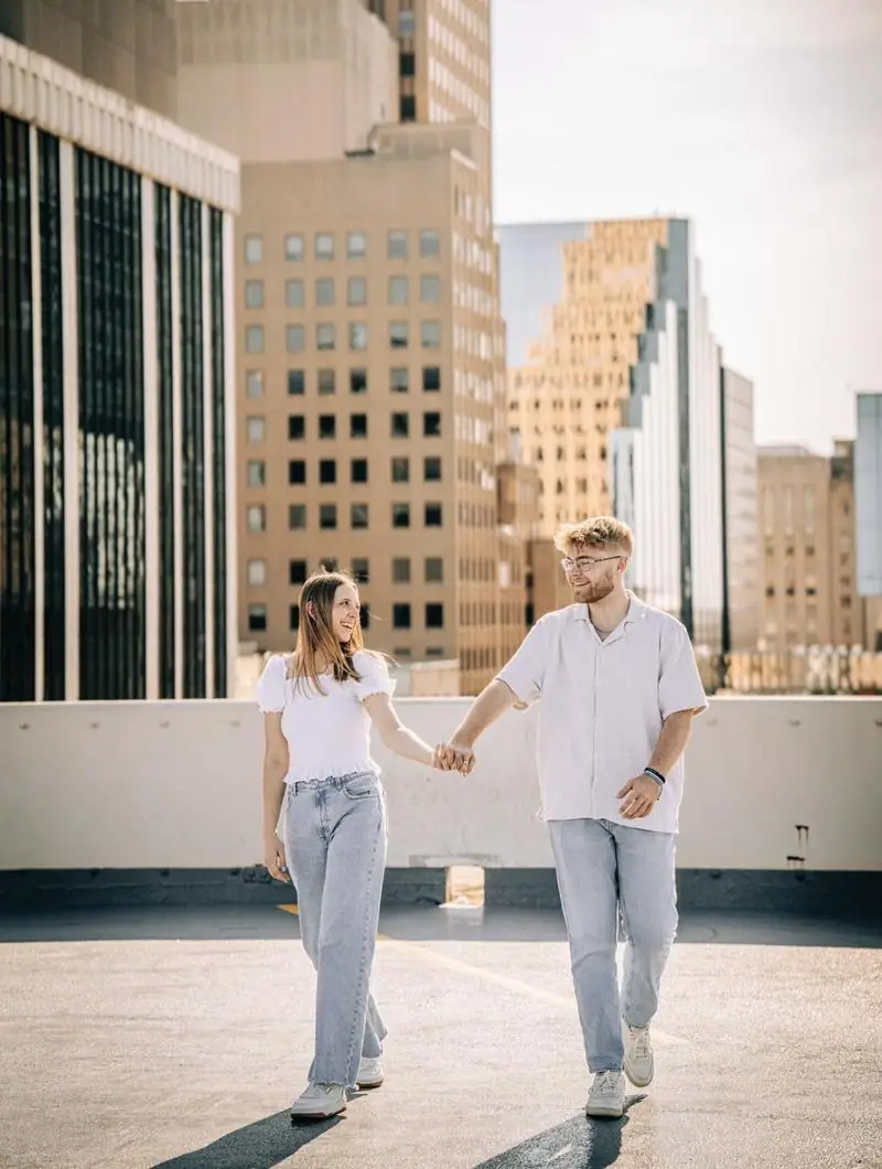 Couple holding hands downtown rooftop engagement Tulsa