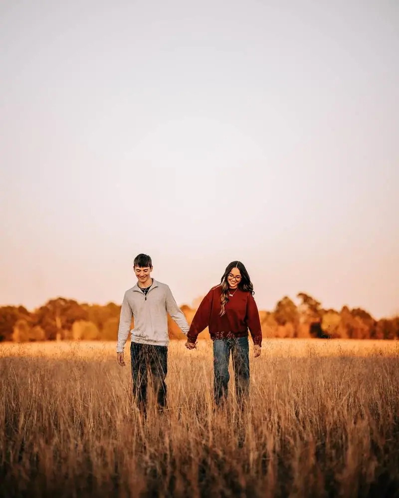 Couple holding hands walking golden field Oklahoma
