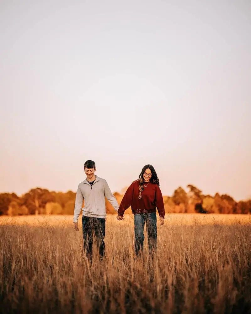 Couple holding hands walking golden field fall mini session Oklahoma City