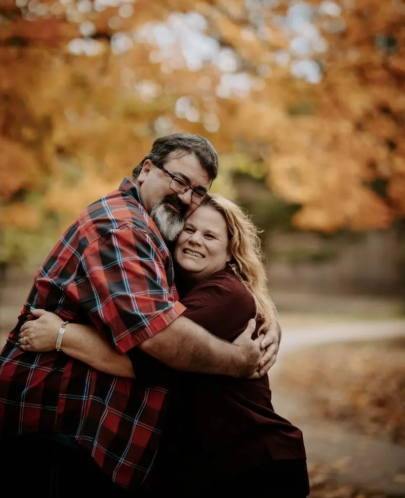 Couple hugging autumn orange trees fall session Oklahoma