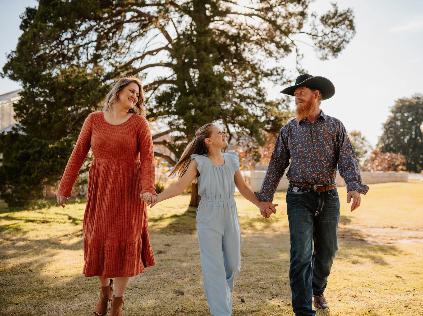 Family of three walking holding hands golden hour Oklahoma family photography