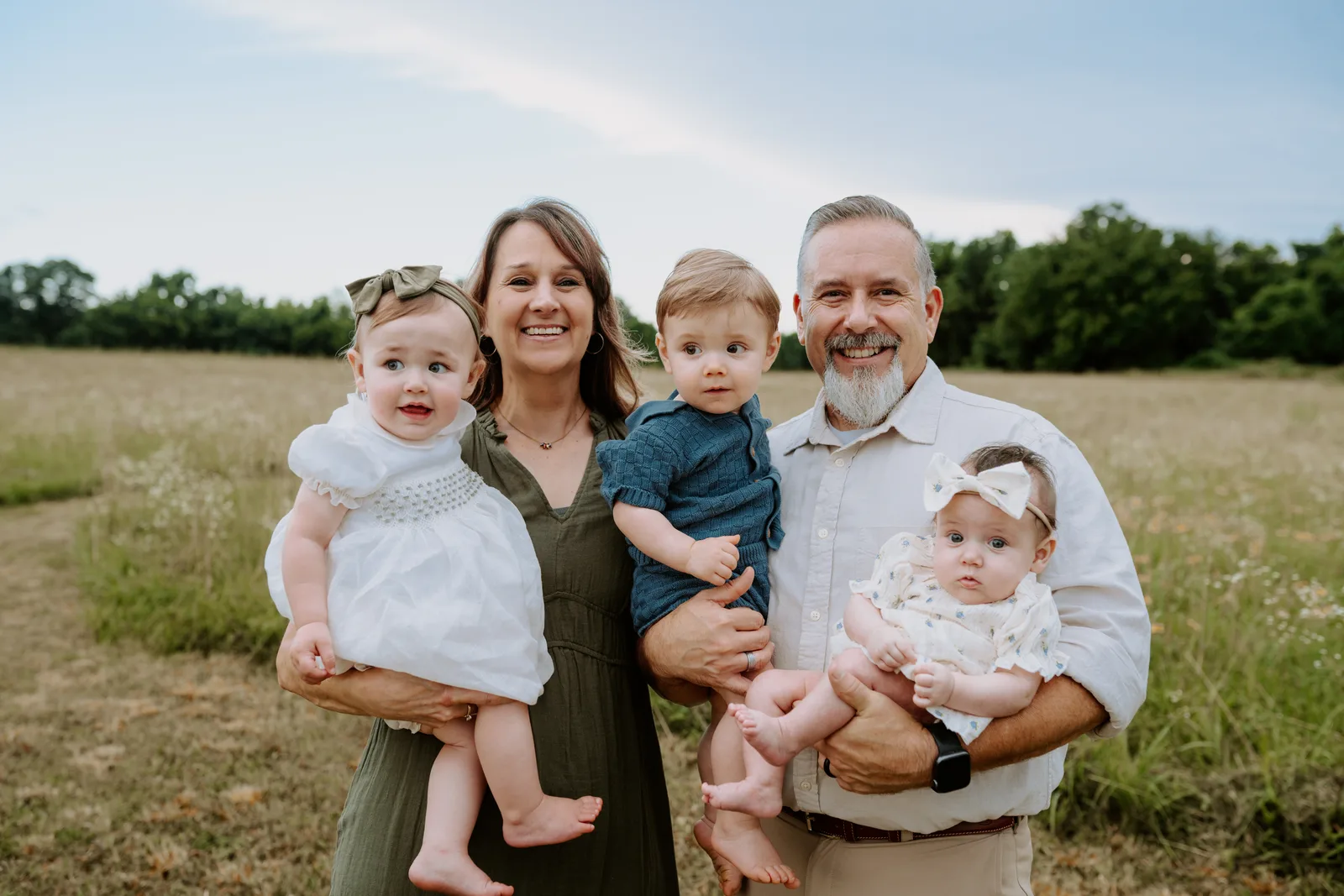 Grandparents holding three grandbabies in field Oklahoma family photography