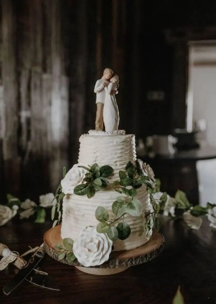 Rustic two tier wedding cake greenery white roses wood stand Oklahoma