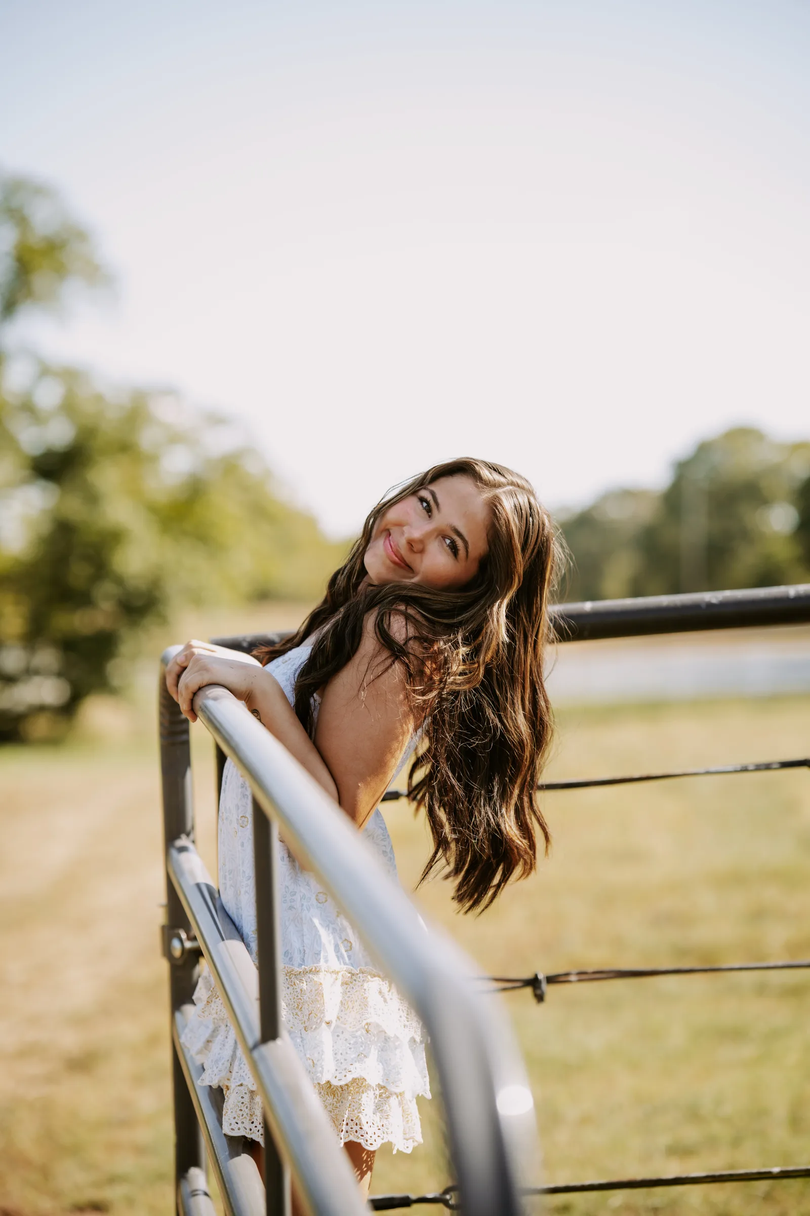 Senior girl white dress on farm gate golden hour Oklahoma
